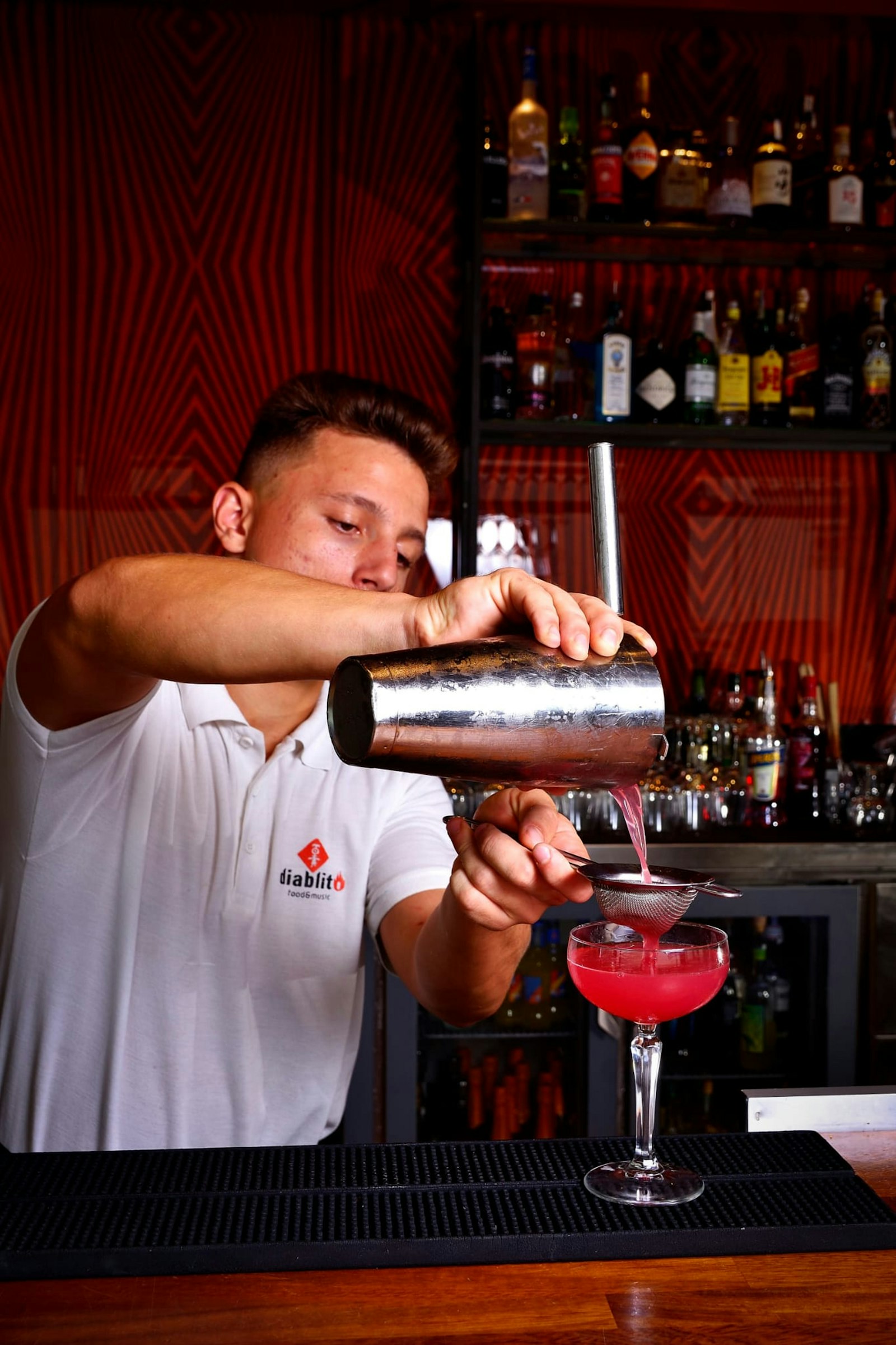 A bartender making a drink behind the bar during service